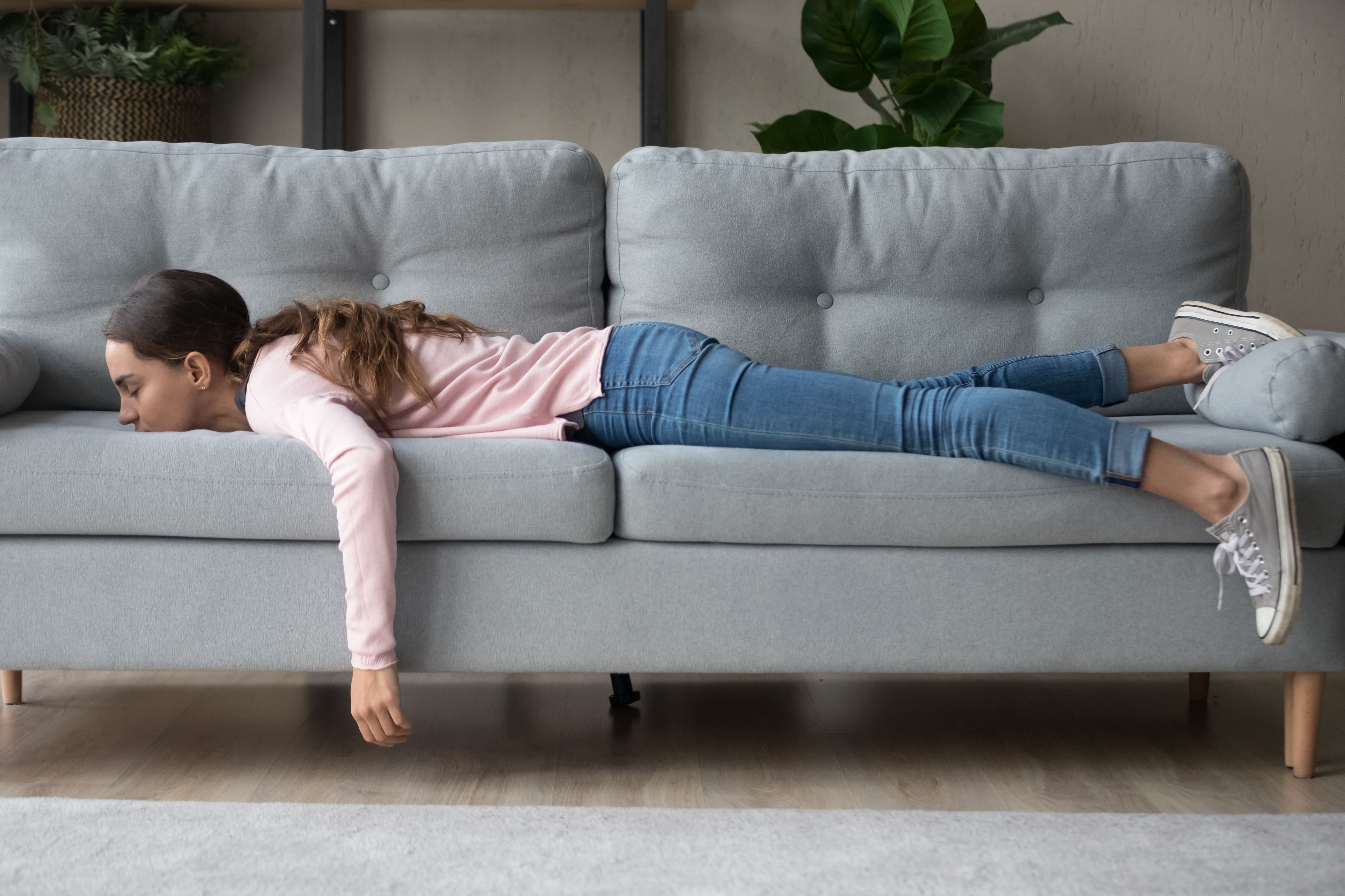 A woman suffering from a lack of sleep lying asleep face down on the couch