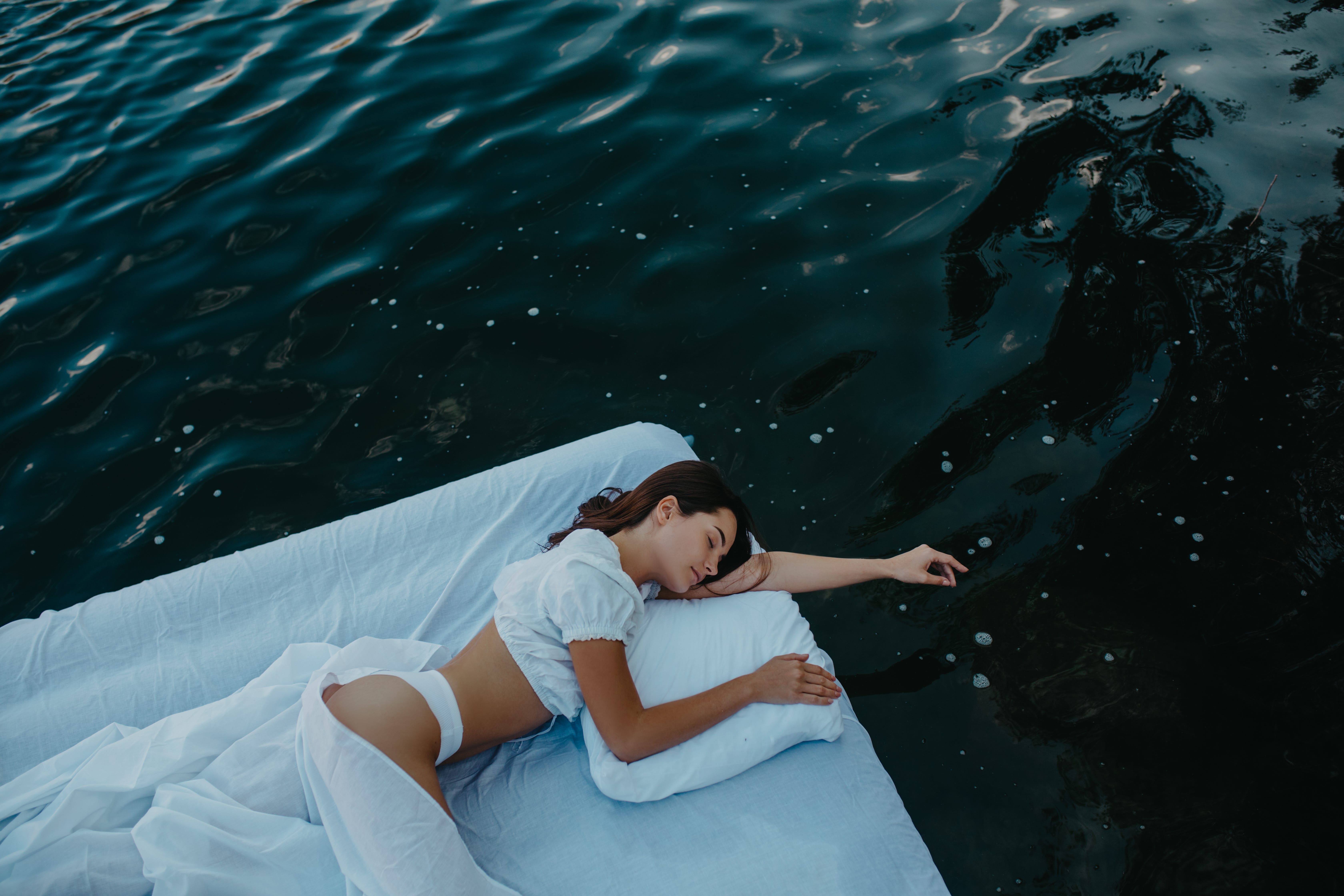 A lady drifting in the water as she sleeps blissfully atop an inflatable mattress.