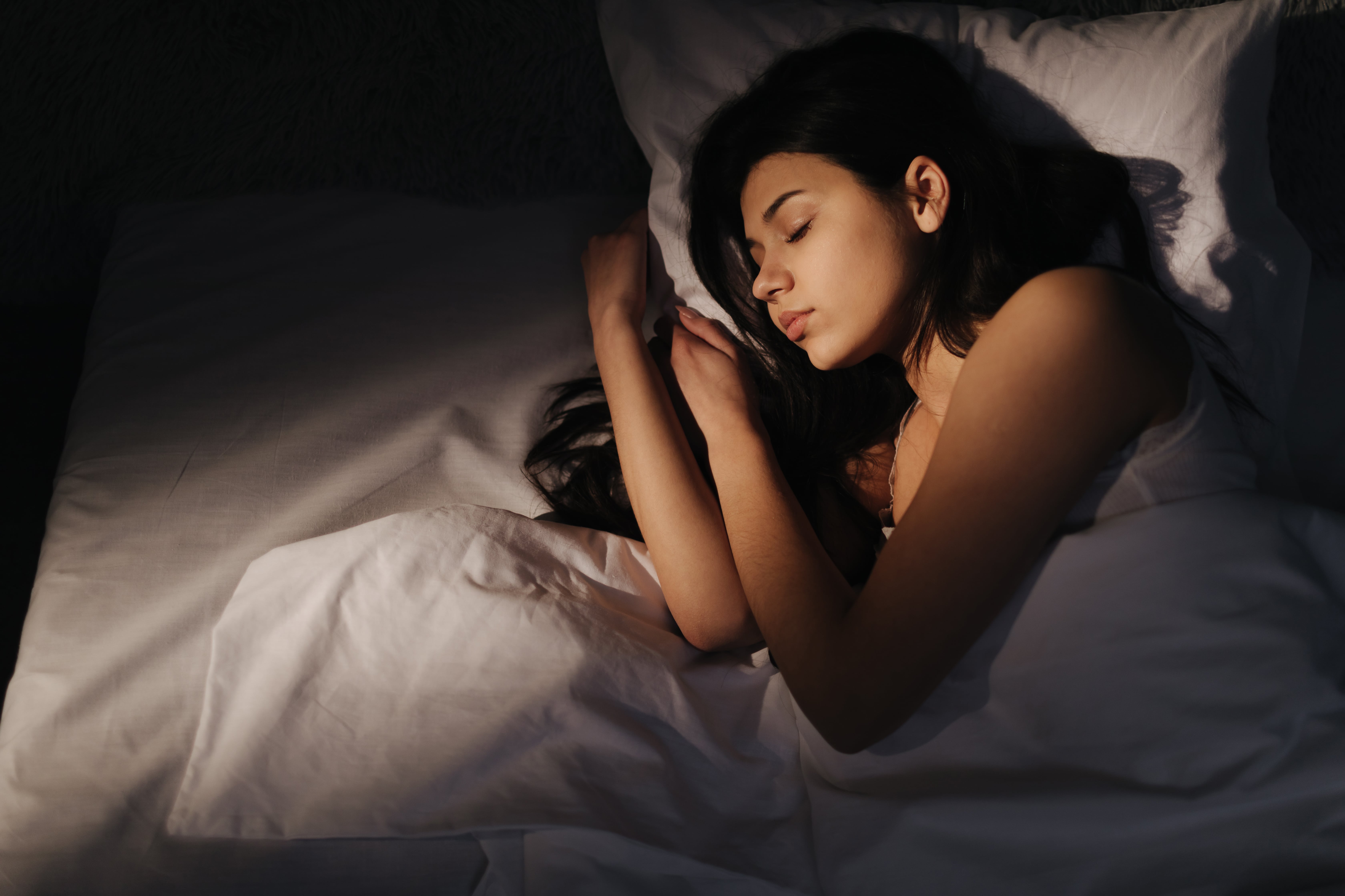 A woman sleeping peacefully on her side in her bed.