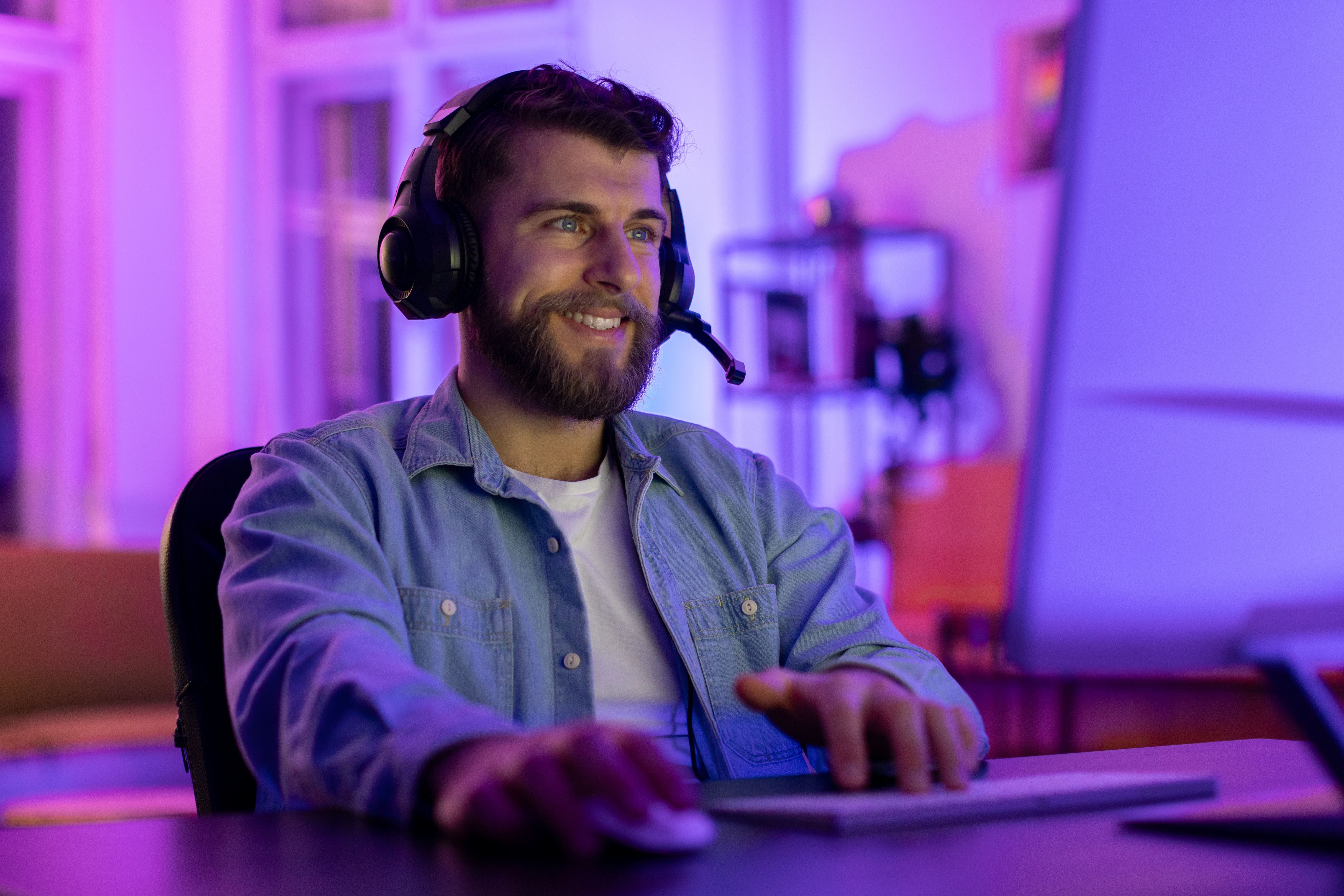 A man enjoying his in-game experience with ambient lighting to enhance his surroundings and a headset so that he is acoustically immersed in the action