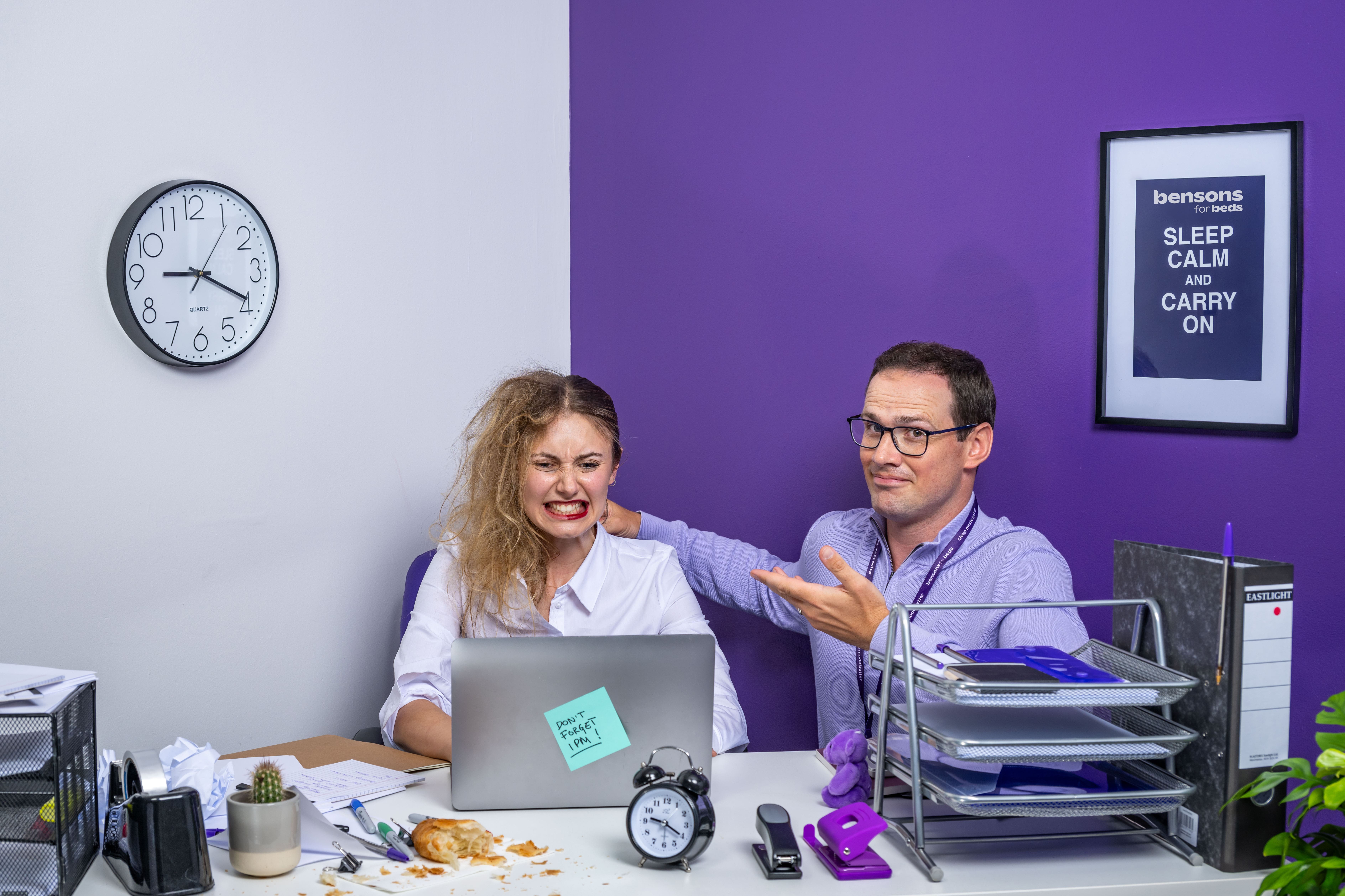 A Bensons for Beds employee sat with the half organised and half chaotic woman at her desk that mirrors this state of flux. He has his hand on her shoulder indicating that he is there to support her. 