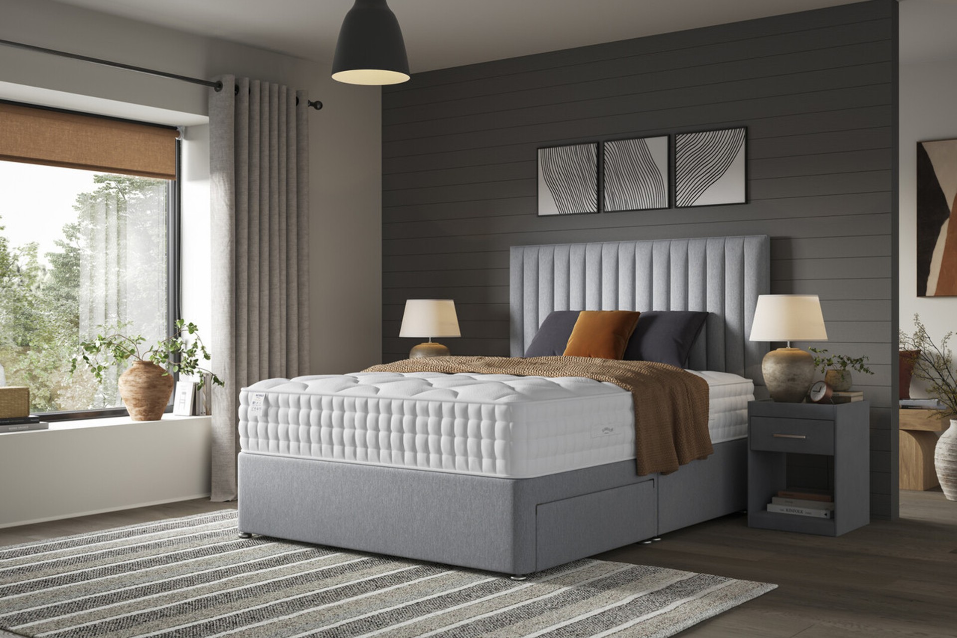 The Ultimate wool mattress on a light grey divan bed base set in a bedroom against a dark grey feature wall